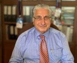 Prof. Dr. İsmail Hakkı Aydın'ın kütüphanesinde veya bilimsel bir kongredeki karizmatik duruşunu simgeleyen portresi.